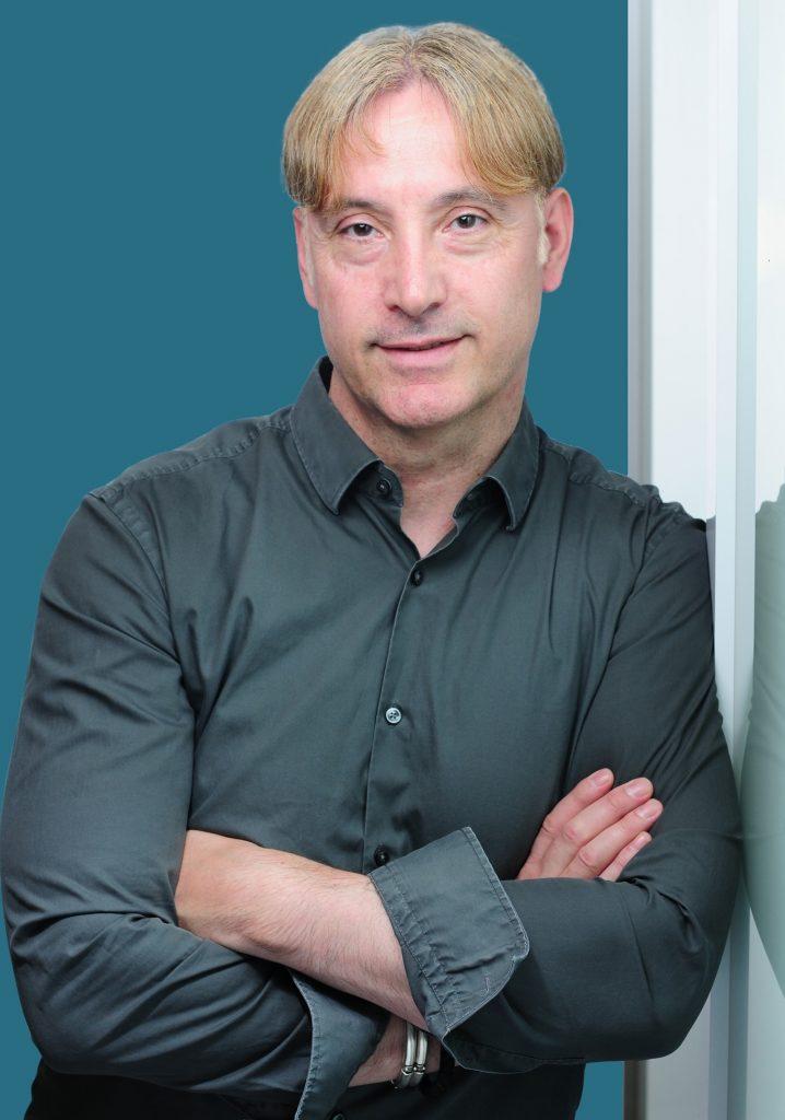 Dr. Alexander Neu in türkisfarbenem Hemd